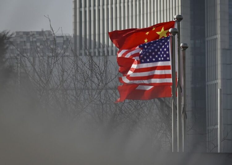 Chinese and US national flags flutter at the entrance of a company office building in Beijing on January 19, 2020. (Photo by WANG ZHAO / AFP)