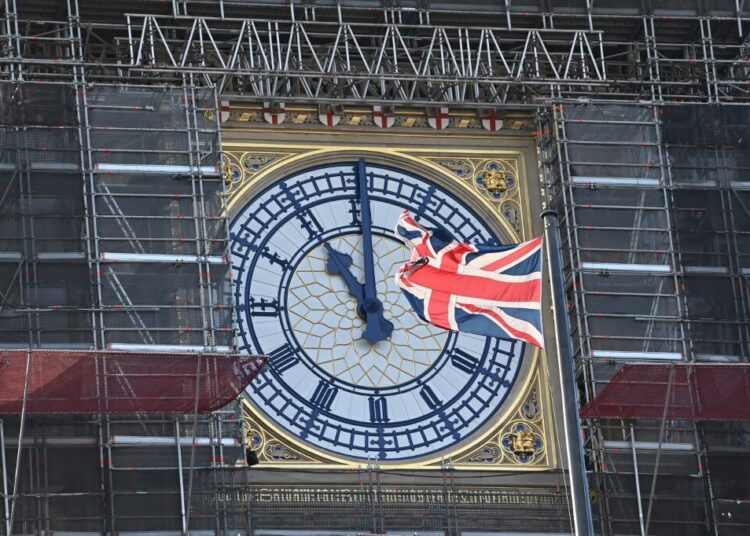 The clock face of Elizabeth Tower, known after the bell Big Ben, shows the hands at eleven o'clock as a Union Flag flies in front of it in London on January 28, 2020. - Britain will formally leave the European Union at 11pm GMT on January 31, 2020. (Photo by Justin TALLIS / AFP)
