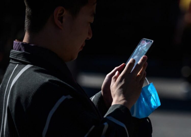 A man holding a face mask uses his mobile phone at Sensoji temple in Tokyo on March 3, 2020. (Photo by Philip FONG / AFP)