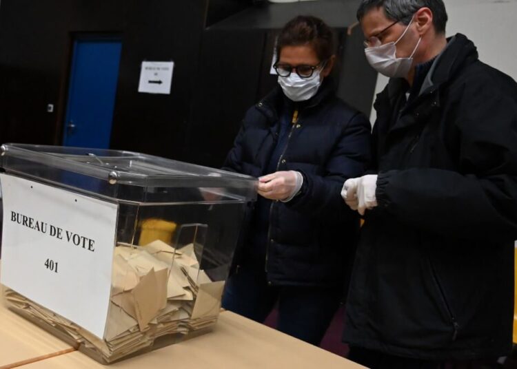 Electoral workers wearing protective masks and plastic gloves carry out the counting of ballots after the first round of Frane's mayoral elections at a polling station in Strasbourg, eastern France, on March 15, 2020. - France voters cast their ballots in municipal elections on March 15 expected to see the lowest turnout in decades, after the mounting coronavirus toll forced the government to close all bars, restaurants and other non-essential businesses in a bid to limit the outbreak. (Photo by Frederick Florin / AFP)