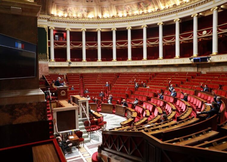 Deputies raise their hands and vote on an emergency law to face the spread of the COVID-19 infection caused by the novel coronavirus at the French National Assembly in Paris on March 22, 2020. (Photo by Ludovic MARIN / AFP)