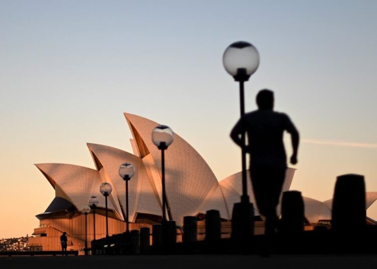 "Sunset hues fall on the landmark Sydney Opera House as a man jogs on Circular Quay"