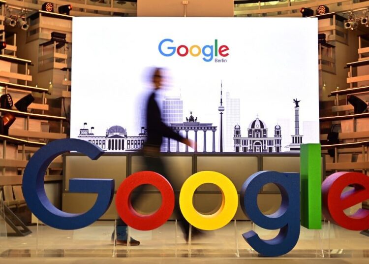 (FILES) In this file photo taken on January 22, 2019 a technician passes by a logo of US internet search giant Google during the opening day of a new Berlin office of Google in Berlin. - Google will pay partnered media publishers in three countries and offer some users free access to paywalled news sites, the tech giant said June 25, 2020. The announcement comes after legal battles in France and Australia over Google's refusal to pay news organizations for content.In a blog post the firm said they would launch "a licensing program to pay publishers for high-quality content for a new news experience" due to launch later this year. (Photo by Tobias SCHWARZ / AFP)