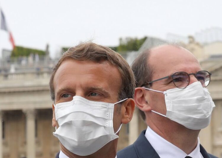 French President Emmanuel Macron (C) and French Prime Minister Jean Castex both wearing a protective facemask react at the end of the annual Bastille Day military ceremony on the Place de la Concorde in Paris, on July 14, 2020. - France holds a reduced version of its traditional Bastille Day parade this year due to safety measures over the COVID-19 (novel coronavirus) pandemic, and with the country's national day celebrations including a homage to health workers and others fighting the outbreak. (Photo by Ludovic Marin / POOL / AFP)