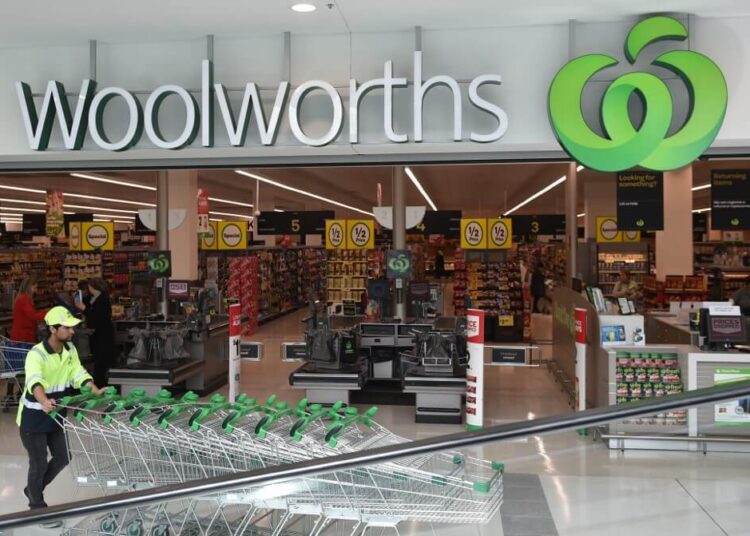 A worker pushes shopping trollys at a Woolworths store in Sydney on August 25, 2016. - Australian supermarket giant Woolworths on August 25 reported a large annual net loss of AUD 1.23 billion (USD 940 million), its first since listing more than two decades ago, following a failed push into hardware and a slump in food sales. (Photo by PETER PARKS / AFP)