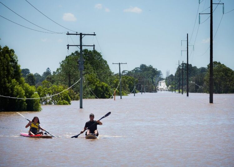 Kayakers paddle on the flooded Logan River, caused by Cyclone Debbie, as it flows over the Mt Lindesay Highway in Waterford West near Brisbane on April 1, 2017. - Flooded rivers were still rising on April 1 in two Australian states with two women dead and four people missing after torrential rains in the wake of a powerful tropical cyclone. (Photo by Patrick HAMILTON / AFP)