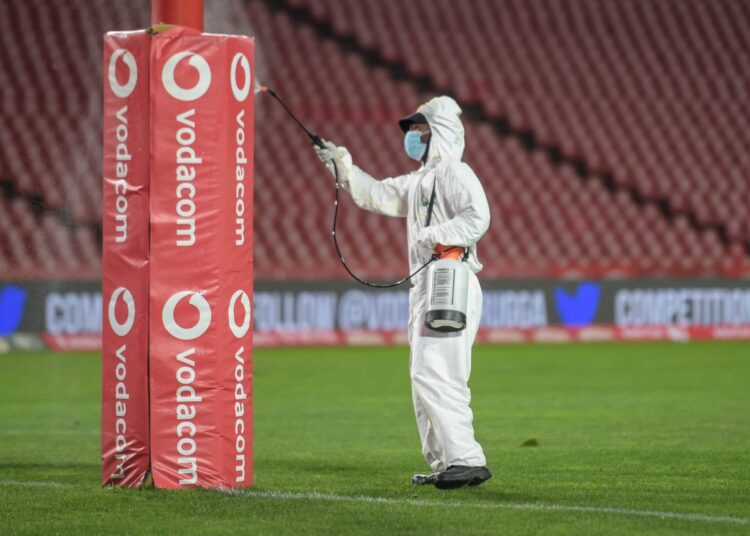 A stadium staff member disinfects the posts against the novel coronavirus Covid-19 at half time during the Super Rugby Unlocked match between the Emirates Lions and the Vodacom Bulls at Emirates Airlines Park stadium in Johannesburg, on November 7, 2020. (Photo by Christiaan Kotze / AFP)