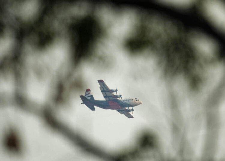 A fire bombing aircraft is seen through the branches of a tree in the suburb of Bullsbrook near Perth on February 3, 2021. (Photo by Trevor Collens / AFP)