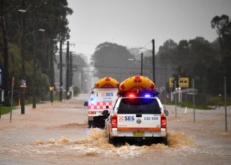State Emergency Service vehicles approach flooded residential areas in western Sydney on March 20, 2021, amid mass evacuations being ordered in low-lying areas along Australia's east coast as torrential rains caused potentially "life-threatening" floods across a region already soaked by an unusually wet summer. (Photo by Saeed KHAN / AFP)