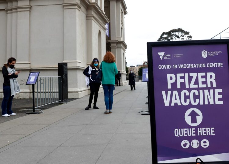 People stand outside a vaccination centre set up at the Melbourne Exhibition Building in Melbourne on August 5, 2021, as authorities there announced a sixth lockdown for the city in efforts to bring the Delta outbreak to heel. (Photo by Con Chronis / AFP)