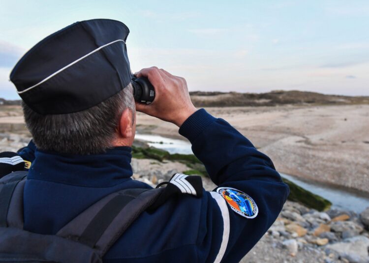 (FILES) In this file photograph taken on April 4, 2019, a French Gendarme looks through a pair of binoculars during a patrol of the beaches at Tardinghen near the northern port city of Calais. - For a year, these "land" gendarmes have been carrying out surveillance, intelligence and rescue missions in the 300-metre strip along the Opal coast. (Photo by Denis Charlet / AFP)