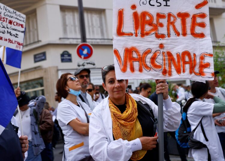 A woman holds a sign reading 'Vaccination freedom' during a protest against the compulsory Covid-19 vaccination for certain workers, and the mandatory use of the health pass called by the French government to access most public spaces, in front of the Health Ministry in Paris on September 11, 2021. (Photo by Thomas SAMSON / AFP)