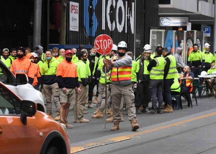 Construction workers take their lunch break on a busy street, disrupting traffic in Melbourne on September 17, 2021, to protest the closing of their onsite tea rooms by health officials amid growing Covid-19 clusters linked to the construction industry. (Photo by William WEST / AFP)