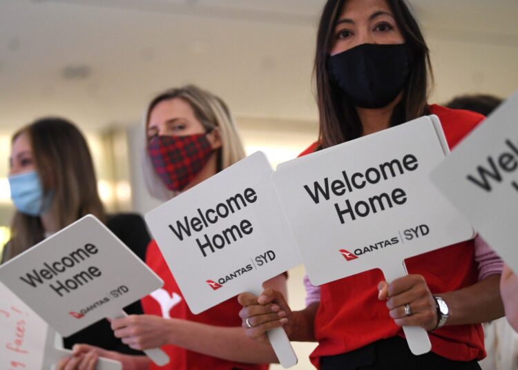 Qantas staff welcome the passengers of Los Angeles flight at the arrival gates of the Sydney International airport on November 1, 2021, after Australia relaxed mandatory quarantine restrictions. (Photo by Saeed Khan / AFP)