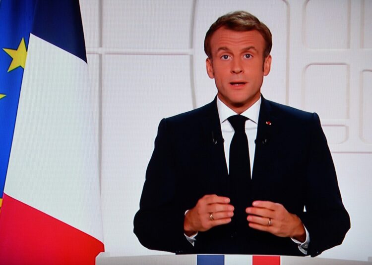 France's President Emmanuel Macron appears on a TV screen as he addresses to the nation on Covid-19 and reforms in Paris on November 9, 2021. - For the ninth time since the beginning of the Covid-19 crisis, Emmanuel Macron solemnly addresses the French to boost the vaccine recall in the face of the rebound of the epidemic, to boast of his record and to evoke the priorities of the end of the five-year term. (Photo by Christophe ARCHAMBAULT / AFP)