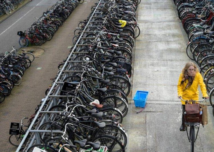 A woman rides a bike in a bicycle outside parking in Amsterdam, western Netherlands, on November 25, 2021. (Photo by SEBASTIEN BOZON / AFP)