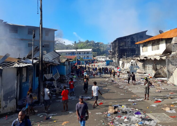 Smoke rises from a burnt out buildings in Honiara's Chinatown on November 26, 2021 after two days of rioting which saw thousands ignore a government lockdown order, torching several buildings around the Chinatown district including commercial properties and a bank branch. (Photo by CHARLEY PIRINGI / AFP)