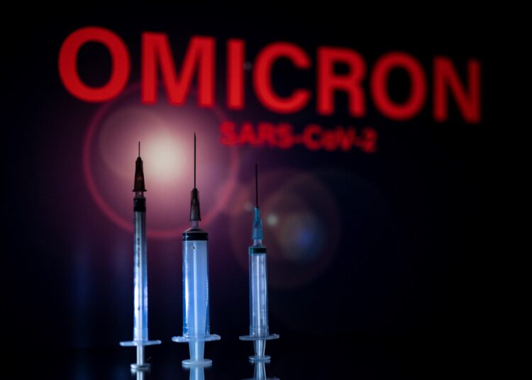 This photograph taken on December 1, 2021 shows syringes and a screen displaying Omicron,  the name of the new covid 19 variant in Toulouse, southwestern France. (Photo by Lionel BONAVENTURE / AFP)