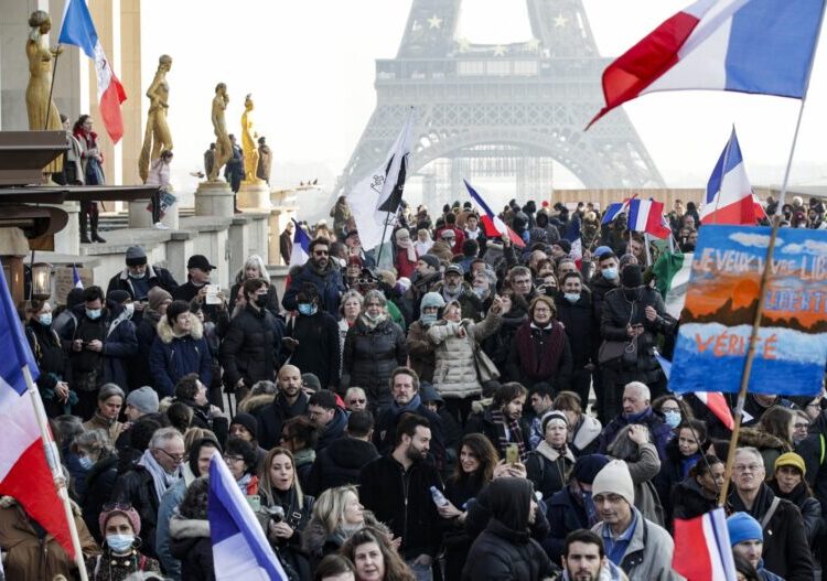 Protesters hold placards and French flgas during a demonstration against the health pass and Covid-19 vaccines, on Trocadero plaza in Paris, on January 15 2022. - Tens of thousands of health passes are expected to be deactivated due to the lack of a Covid vaccine reminder on January 15, 2022, the deadline set by the government, against the backdrop of new demonstrations by opponents of this device and the vote on the controversial bill on the pass in the Assembly. (Photo by GEOFFROY VAN DER HASSELT / AFP)