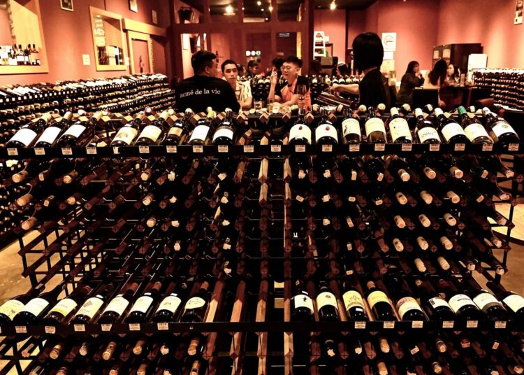 Racks of wine are displayed as customers enjoy a meal at a restaurant in Penang on July 20, 2020, as Malaysia continues to reopen after months of lockdown due to the COVID-19 novel coronavirus. (Photo by GOH Chai Hin / AFP)