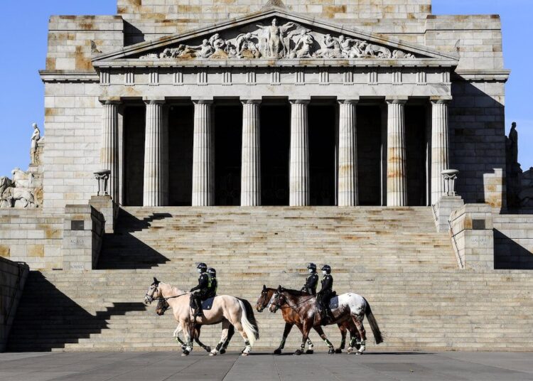 Police on horseback patrol The Shrine of Remembrance enforcing people to wear face masks in Melbourne on July 31, 2020. - As greater Melbourne passed the halfway point of a lockdown initially intended to last six weeks, the state of Victoria - of which Melbourne is the capital - recorded over 600 new cases leaving Premier Daniel Andrews to flag harsher restrictions in a bid to cut the infection rate. (Photo by William WEST / AFP)