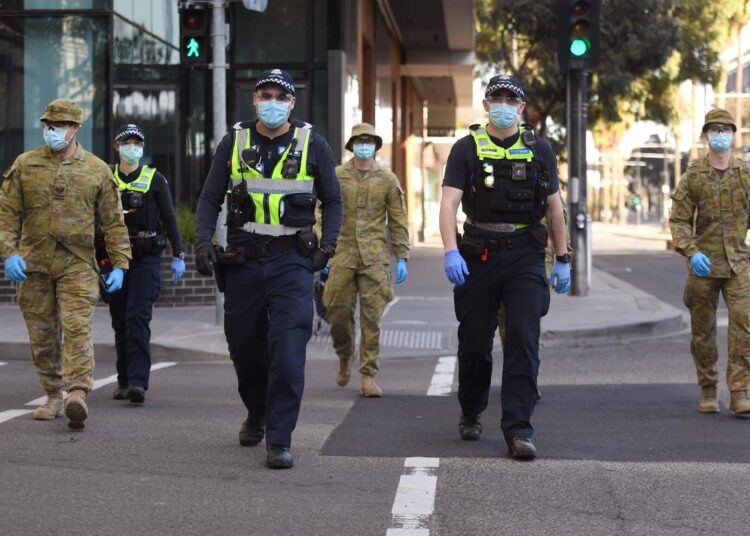 A group of police and soldiers patrol the Docklands area of Melbourne on August 2, 2020, after the announcement of new restrictions to curb the spread of the COVID-19 coronavirus. - Australia on August 2 introduced sweeping new measures to control a growing coronavirus outbreak in its second-biggest city, including an overnight curfew and a ban on weddings for the first time during the pandemic. (Photo by William WEST / AFP)
