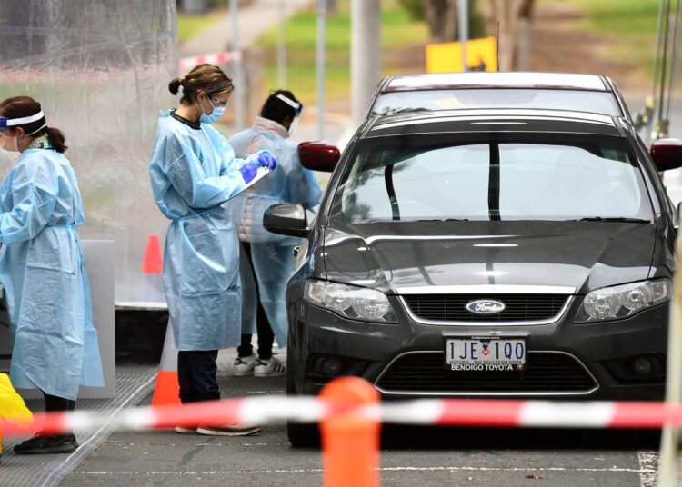 Medical staff prepare to take a swab at a drive-through testing clinic in Melbourne on August 13, 2020. - Australia's virus-hit Victoria state reported a major drop in new coronavirus cases on August 13, but officials warned against complacency amid a "worrying" spread of the disease in regional areas outside Melbourne. (Photo by William WEST / AFP)