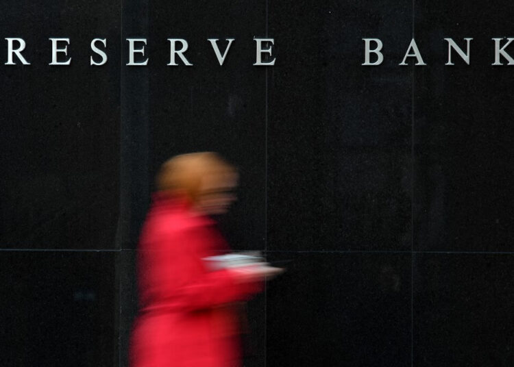 People walk past the Reserve Bank of Australia building in Sydney on May 7, 2019. as Australia's central bank kept interest rates on hold. - The Reserve Bank of Australia left interest rates on hold bucking calls for a cut to protect the country's 27-year recession-free run. (Photo by Saeed KHAN / AFP)