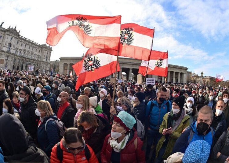 (FILES) In this file photo taken on November 20, 2021 demonstrators wave Austrian flags with the emblem turned upside down during a rally held by Austria's far-right Freedom Party FPOe against the measures taken to curb the coronavirus (Covid-19) pandemic, at Heldenplatz square in front of the Hofburg Palace in Vienna, Austria. - Austria's parliament on January 20, 2022 approved making Covid-19 vaccinations mandatory for adults from next month, becoming the first European country to do so despite a wave of protests opposing the measure. Tens of thousands have demonstrated against mandatory vaccination in regular weekend rallies since the measure was announced in November in a bid to drive up the country's vaccination rate. (Photo by Joe Klamar / AFP)