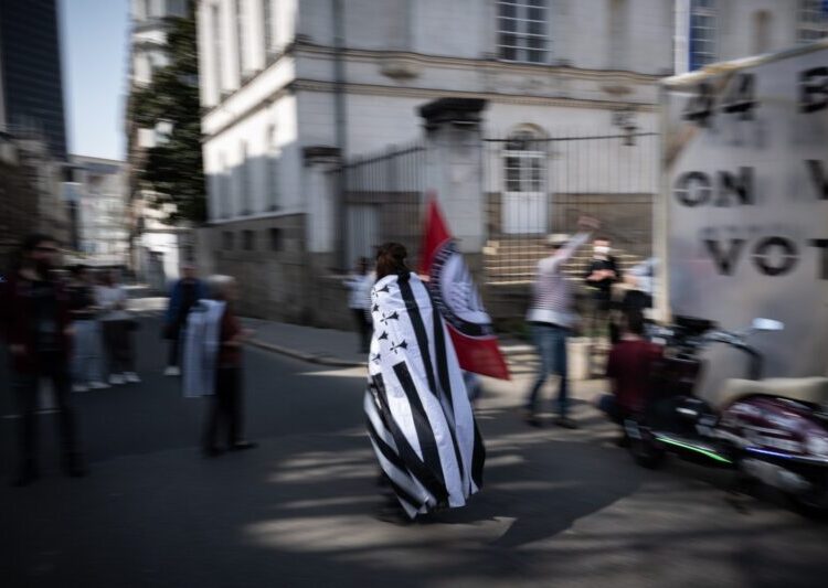 A woman wears a "Gwenn ha du", the French Brittany's flag, western France, on March 27, 2022, during a demonstration in order to ask for a referendum on the attachment of the Loire-Atlantique department in the Bretagne region. (Photo by Loic VENANCE / AFP)