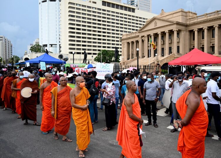 Buddhist monks take part in a demonstration against the economic crisis at the entrance of the president's office in Colombo on April 12, 2022. - Sri Lanka announced a default on its $51 billion foreign debt on April 12 as the island nation grapples with its worst economic crisis in memory and escalating protests demanding the government's resignation. (Photo by Ishara S. KODIKARA / AFP)