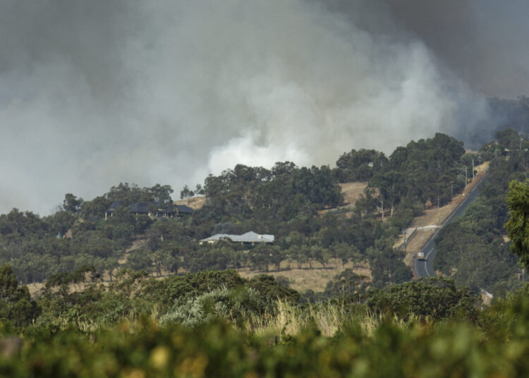 Smoke rises behind a hill as a house is threatened by fires in the suburb of Baskerville near Perth on February 3, 2021. (Photo by Trevor Collens / AFP)