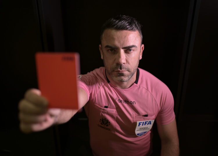 Brazilian football referee Igor Benevenuto shows a red card as he poses for a picture at the dressing room of the Mineirao stadium, in Belo Horizonte, Minas Gerais State, Brazil, on August 10, 2022. - In July 2022, Brazilian premier league official Benevenuto came out publicly on a football podcast, joining a very short list of trailblazing referees to publicly identify as gay. Benevenuto sais that after a lifetime hiding his sexuality, he wanted to get the "emotional burden" off his chest and do his part to change the machismo that permeates Brazilian football. (Photo by Douglas MAGNO / AFP)