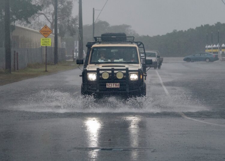 A motorist drives through floodwater as Cyclone Jasper approaches landfall in Cairns in far north Queensland on December 13, 2023. - A tropical cyclone was building strength as it rolled towards northeastern Australia on 13 December, with authorities warning "life-threatening" floods could swamp coastal regions for days. (Photo by Brian CASSEY / AFP)