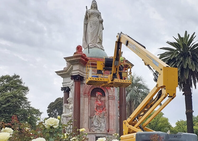 A council worker cleans the statue to Britain's Queen Victoria that was defaced in the Royal Botanic Gardens Victoria in Melbourne on January 25, 2024, ahead of Australia Day. (Photo by Martin PARRY / AFP)